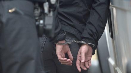 Ein Polizist hält einen Demonstranten in Handschellen fest. Weniger Straftaten, viele Verdächtige aus dem Ausland. 