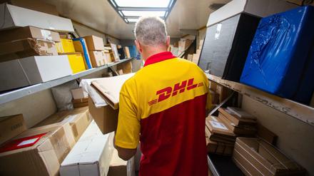Ein Mitarbeiter des Unternehmens Deutsche Post DHL belädt sein Auto.