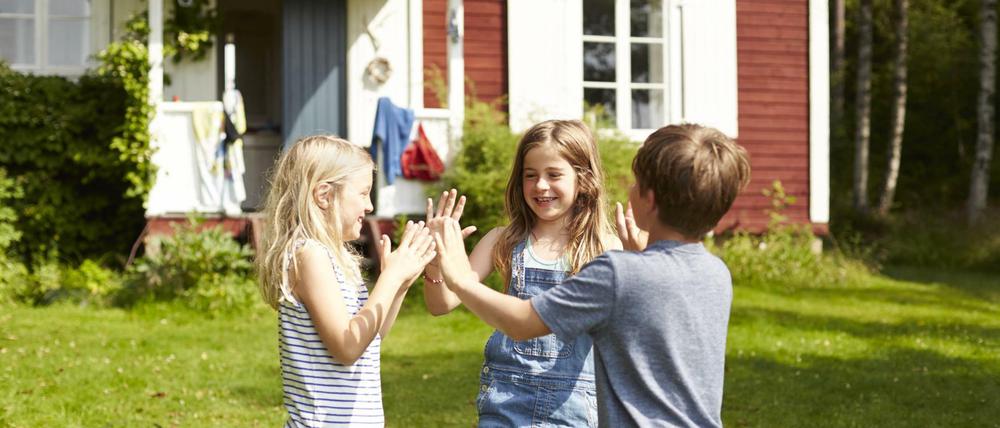 Drei Kinder spielen vor einem Haus (Symbolbild).