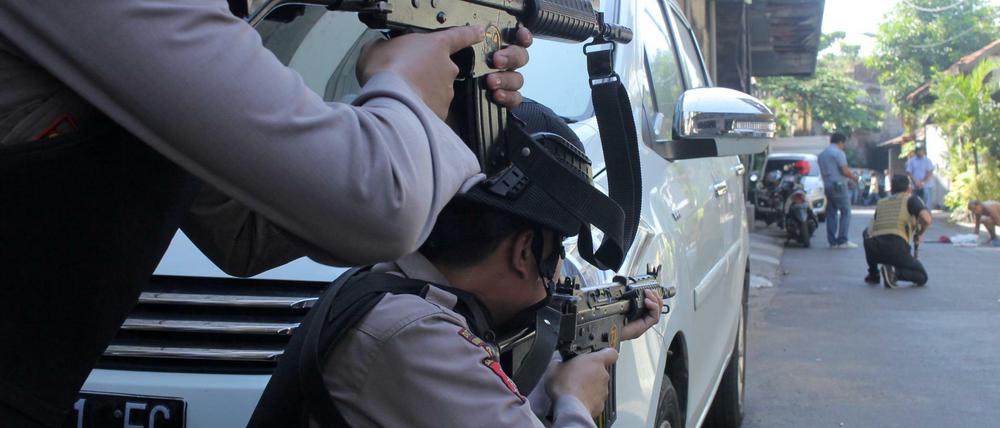 Indonesische Polizisten zielen auf einen Verdächtigen, der nach der Explosion in der Polizeizentrale von Surabaya durchsucht wird.. 