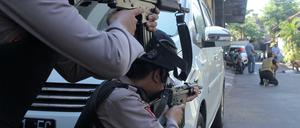 Indonesische Polizisten zielen auf einen Verdächtigen, der nach der Explosion in der Polizeizentrale von Surabaya durchsucht wird.. 
