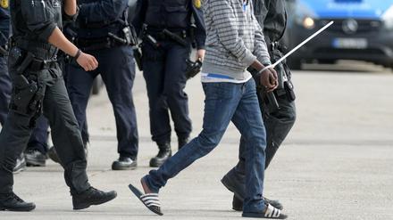 In der Landeserstaufnahmeeinrichtung für Flüchtlinge (LEA) in Ellwangen wird ein gefesselter Mann von maskierten Polizisten abgeführt. 