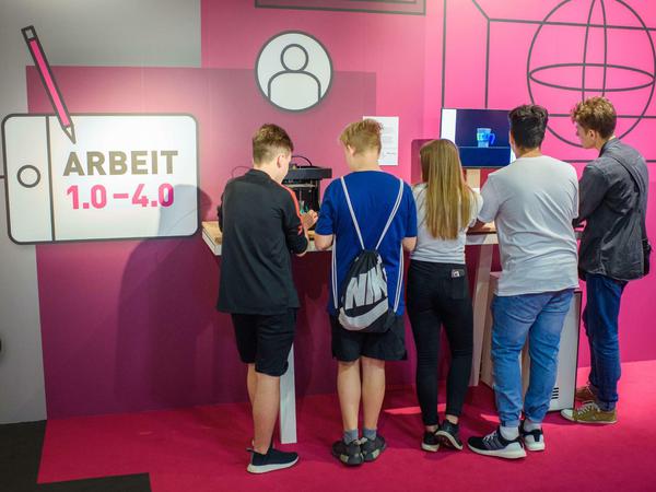  Jugendliche betrachten eine interaktive Station zur Arbeitswelt der Zukunft im Bauch des Ausstellungsschiffes "MS Wissenschaft".