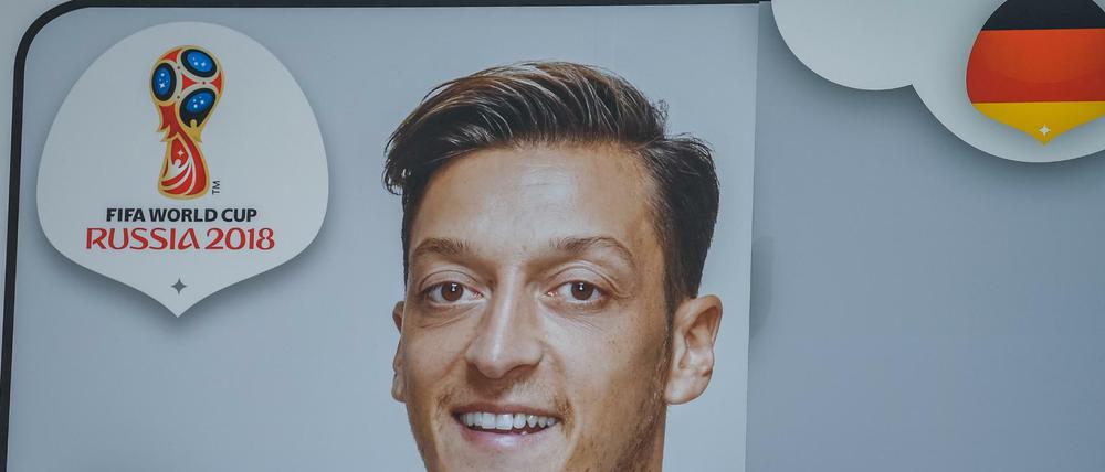 Helfer kleben ein Bild von Mittelfeldspieler Mesut Özil während der DFB-Pressekonferenz an die Außenwand des Fußballmuseums.