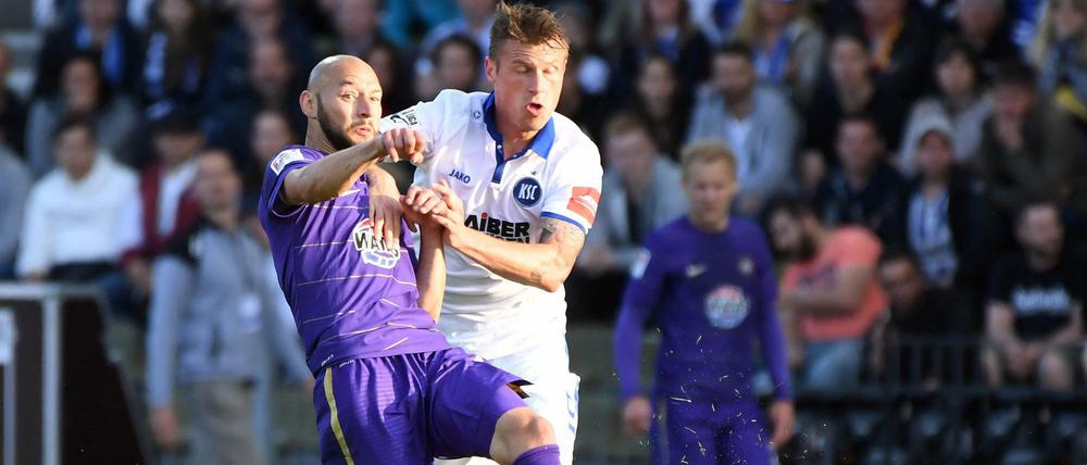 Der Karlsruher Marvin Pourie (r) und der Auer Philipp Riese kämpfen um den Ball. 