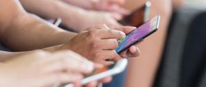 Menschen tippen auf ihre Smartphones (Symbolbild).