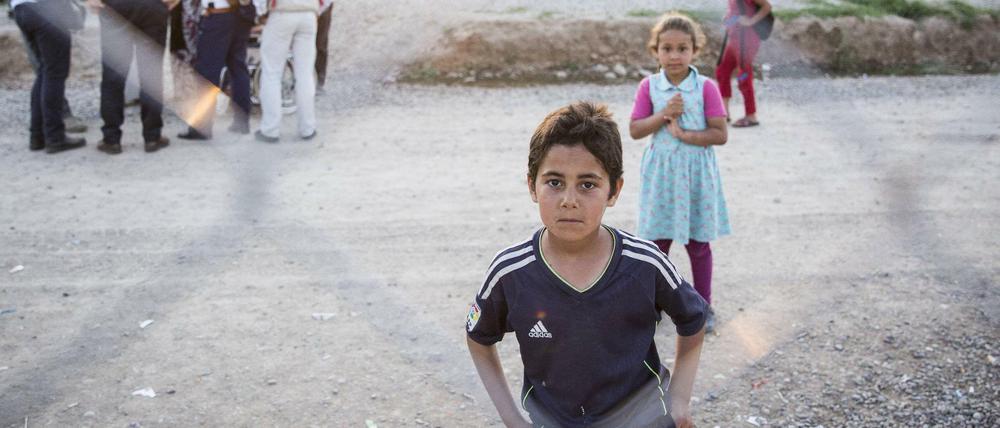 Kinder stehen hinter dem Zaun eines Flüchtlingslagers im Irak.