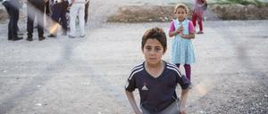 Kinder stehen hinter dem Zaun eines Flüchtlingslagers im Irak.