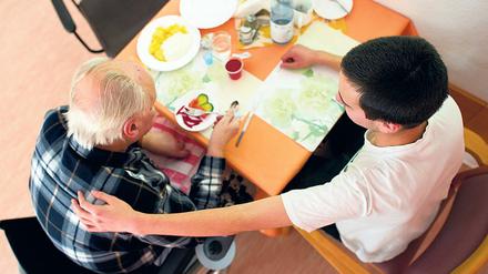 In einem Seniorenheim betreut ein Teilnehmer des Bundesfreiwilligendienstes einen Mann.