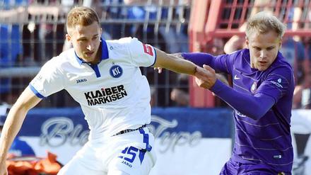 Der Karlsruher Jonas Föhrenbach (l) und der Auer Sören Bertram kämpfen um den Ball. 