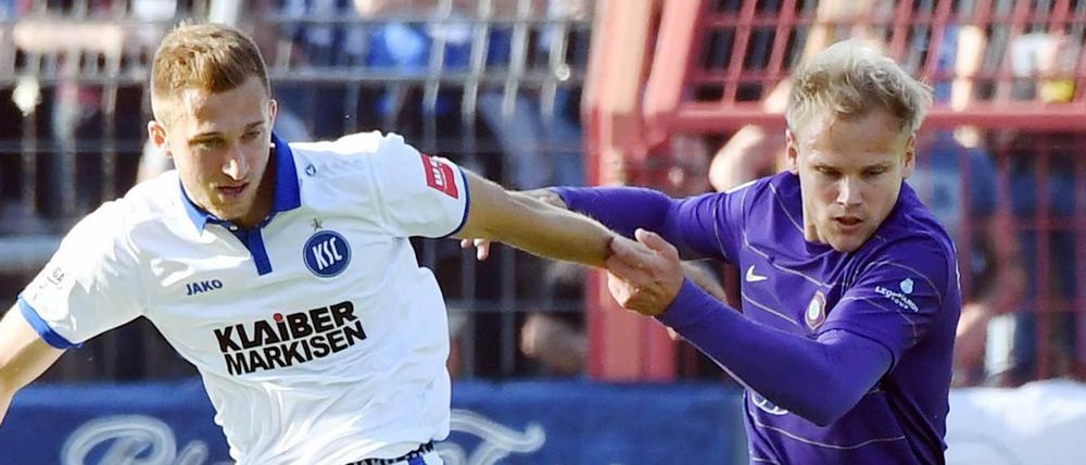 Der Karlsruher Jonas Föhrenbach (l) und der Auer Sören Bertram kämpfen um den Ball. 