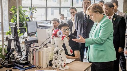 Bundeskanzlerin Angela Merkel (CDU) besichtigt das Startup iCarbonX und spricht mit einem Programmierer am Computer. 