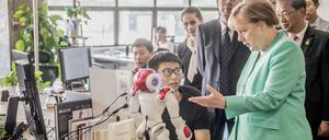 Bundeskanzlerin Angela Merkel (CDU) besichtigt das Startup iCarbonX und spricht mit einem Programmierer am Computer. 
