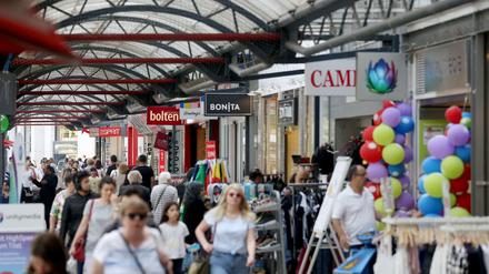 Unter der zum Teil überdachten Einkaufsstraße in der Innenstadt von Duisburg sind Passanten unterwegs. Hier darf man jetzt wieder trinken.