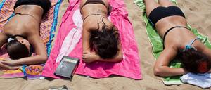 Frauen liegen am Strand des Helenesees in der Sonne. 