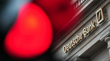 Eine rote Ampel leuchtet in Frankfurt am Main vor einer Filiale der Deutschen Bank.