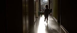 Die Silhouette eines Kleinkinds ist im im Gegenlicht in einem Flur zu sehen.