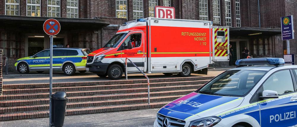Rettungskräfte und Polizisten stehen vor dem Bahnhof in Flensburg