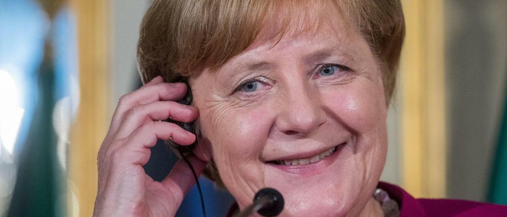 Bundeskanzlerin Angela Merkel hält sich bei einer Pressekonferenz bei ihrem Besuch in Portugal im Palácio Foz einen Kopfhörer ans Ohr.