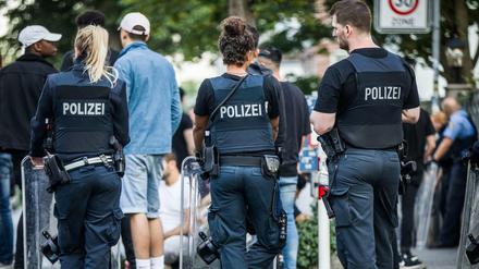 Polizisten bewachen am frühen Morgen eine Gruppe festgesetzter junger Männer neben dem Herrngarten am Rande der Innenstadt. 