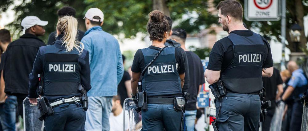 Polizisten bewachen am frühen Morgen eine Gruppe festgesetzter junger Männer neben dem Herrngarten am Rande der Innenstadt. 