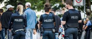 Polizisten bewachen am frühen Morgen eine Gruppe festgesetzter junger Männer neben dem Herrngarten am Rande der Innenstadt. 