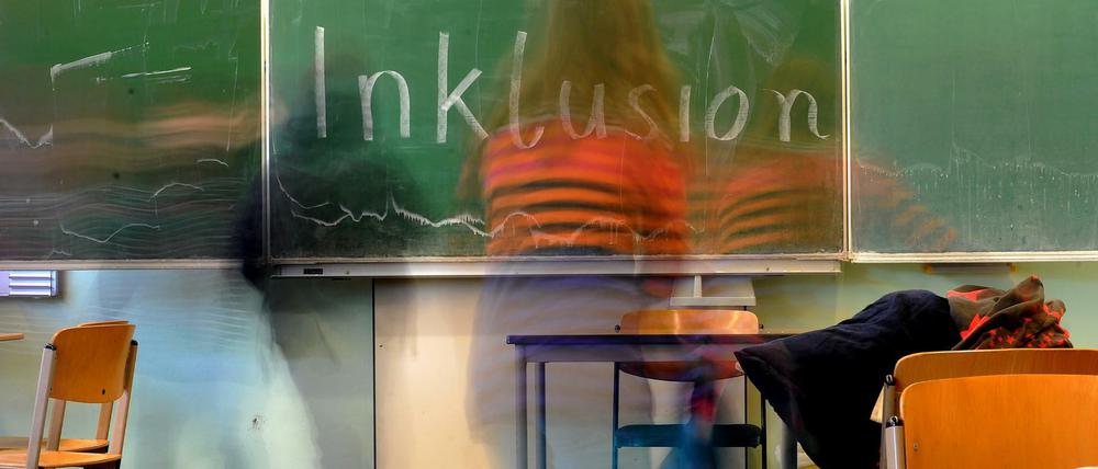 Auf einer aufgeklappten Tafel in einem Klassenraum steht "Inklusion".