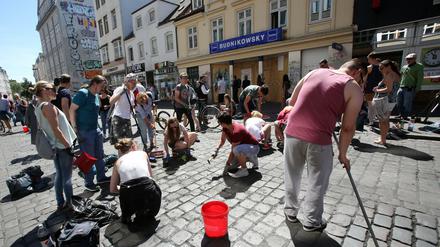 Teilnehmer eines Aufräumaktion putzen im Juli 2017 das Schulterblatt im Schanzenviertel in Hamburg. Im Hintergrund ist die Filiale der Drogeriekette Budnikowsky zu sehen, die in der Nacht zum 8. Juli geplündert und verwüstet wurde.