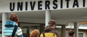 Eine Gruppe von Studierenden geht auf das Hauptgebäude einer Universität zu.