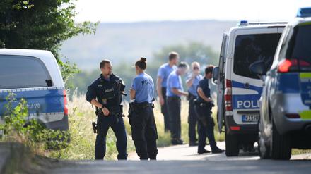 Polizisten warten an einem gesperrten Feldweg im Wiesbadener Stadtteil Erbenheim.