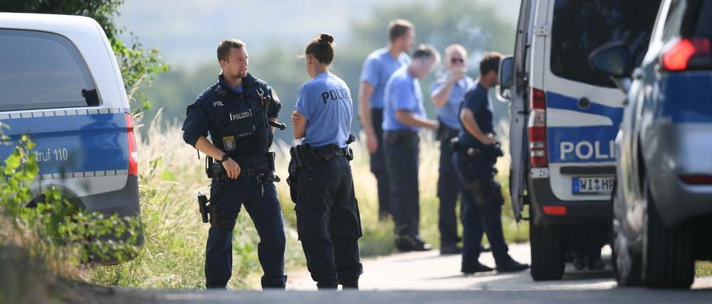 Polizisten warten an einem gesperrten Feldweg im Wiesbadener Stadtteil Erbenheim.