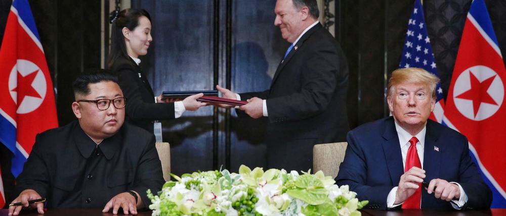 Präsident Donald Trump (r) und der Machthaber von Nordkorea Kim Jong Un (l) unterzeichnen die gemeinsame Vereinbarung.