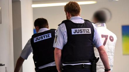 Der Hauptbeschuldigte im Freiburger Missbrauchsprozess wird von Justizbediensteten in den Gerichtssaal gebracht. 