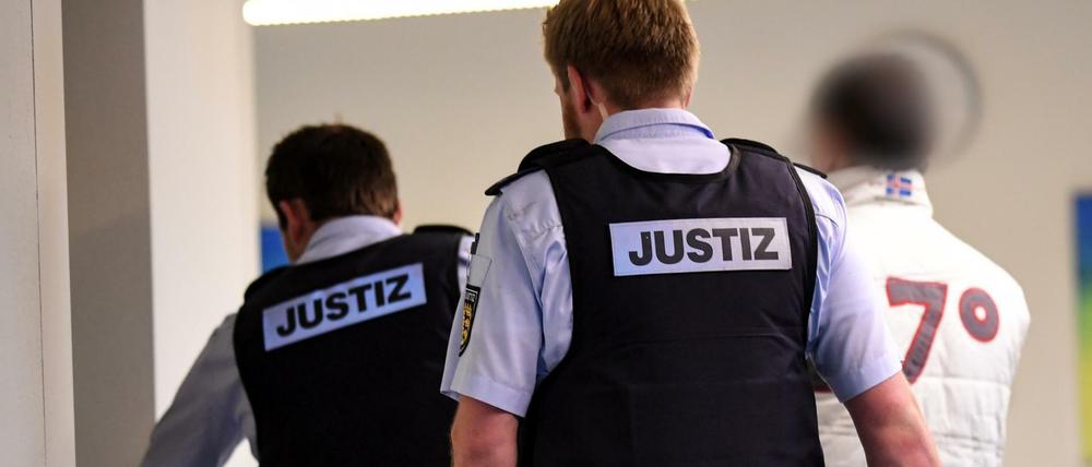 Der Hauptbeschuldigte im Freiburger Missbrauchsprozess wird von Justizbediensteten in den Gerichtssaal gebracht.