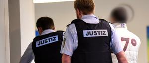 Der Hauptbeschuldigte im Freiburger Missbrauchsprozess wird von Justizbediensteten in den Gerichtssaal gebracht. 