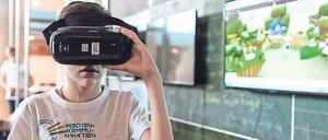 Ein Schulkind probiert im Klassenraum eine Virtual-Reality-Brille aus.