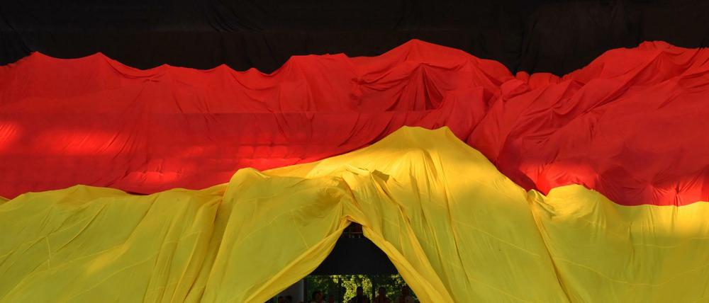 Fußballfans unter einen überdimensionalen Deutschlandflagge bei einem WM-Qualifikationsspiel in Nürnberg.