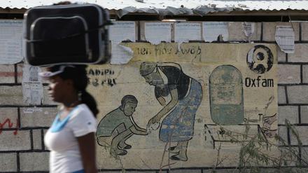 Eine Frau läuft an einem Oxfam-Plakat in Port-au-Prince vorbei, wo Mitarbeiter von Oxfam Sexorgien gefeiert haben.