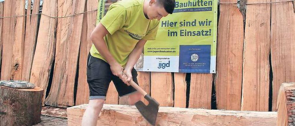 Wie im Mittelalter. Jakob Grohmann (18) ist ganz bei der Sache. Wie auf einem Stich aus dem 12. Jahrhundert – zu sehen im Europäischen Hansemuseum gegenüber in der Abteilung Städtebau – steht er breitbeinig über dem Balken und schwingt das schwere Breitbeil