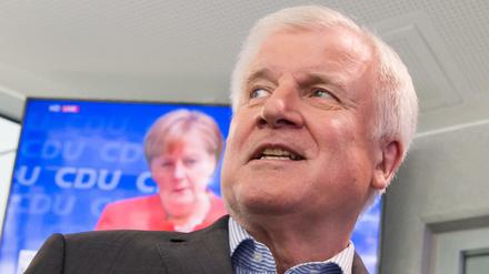 Horst Seehofer läuft auf seinem Weg zur Pressekonferenz an einem Fernseher vorbei, auf dem die Pressekonferenz von Bundeskanzlerin Angela Merkel übertragen wird. 
