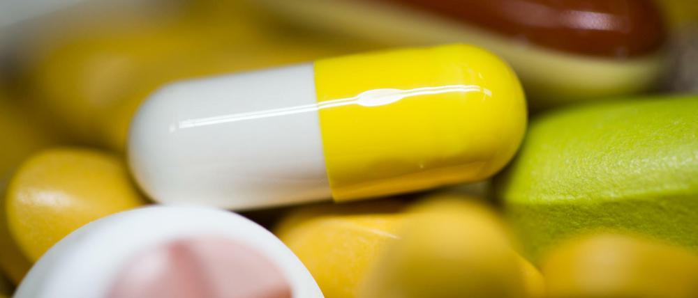 Tabletten, Kapseln und Pillen in verschiedenen Farben liegen in einem Medikamenten-Behälter einer Apotheke. 