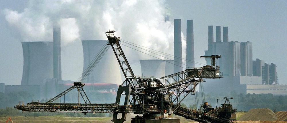 Ein Bagger fährt vor der Kulisse des RWE-Kraftwerkes Niederaußem durch den Tagebau Garzweiler.