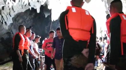 Ein Rettungsteam am Eingang einer Tropfsteinhöhle, in der eine thailändische Jugend-Fußballmannschaft eingeschlossen ist.