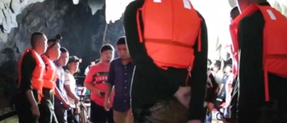 Ein Rettungsteam am Eingang einer Tropfsteinhöhle, in der eine thailändische Jugend-Fußballmannschaft eingeschlossen ist.