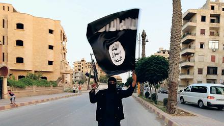 Ein Kämpfer trägt die Flagge des IS im Juni 2014 durch Raqqa. 