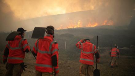 Feuerwehrmänner betrachten Flammen eines Moorbrandes, der sich im Saddleworth Moor und in Richtung der umliegenden Wohngegenden ausbreitet.