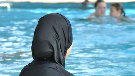 Besser so schwimmen als gar nicht? Ein Mädchen im Burkini am Beckenrand.