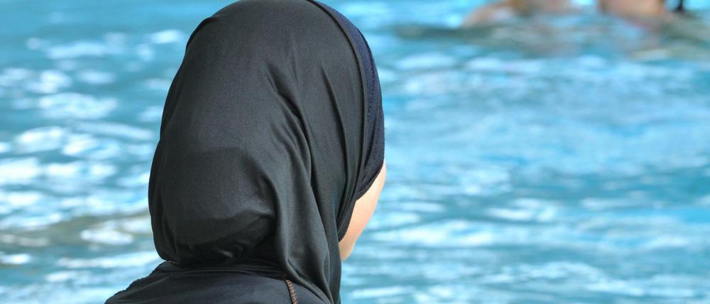 Besser so schwimmen als gar nicht? Ein Mädchen im Burkini am Beckenrand.