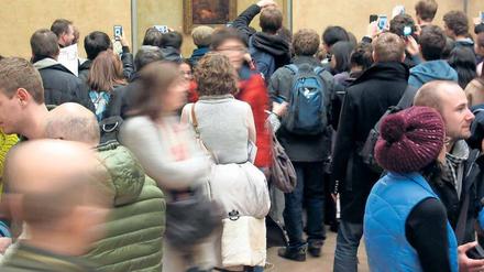 Besuchermassen stehen im Louvre vor dem Bildnis der Mona Lisa.