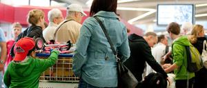 Passagiere warten mit ihrem Gepäck an einem Check-in-Schalter im Flughafen Tegel (Symbolbild).